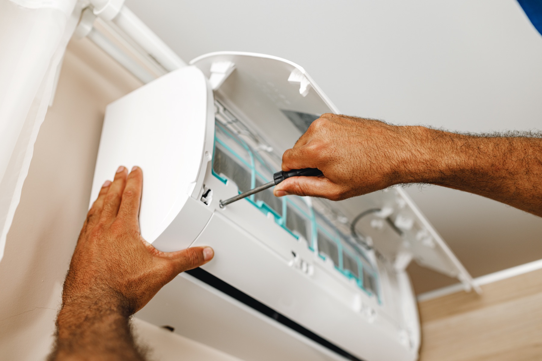 Hands using a screwdriver on indoor cooling equipment