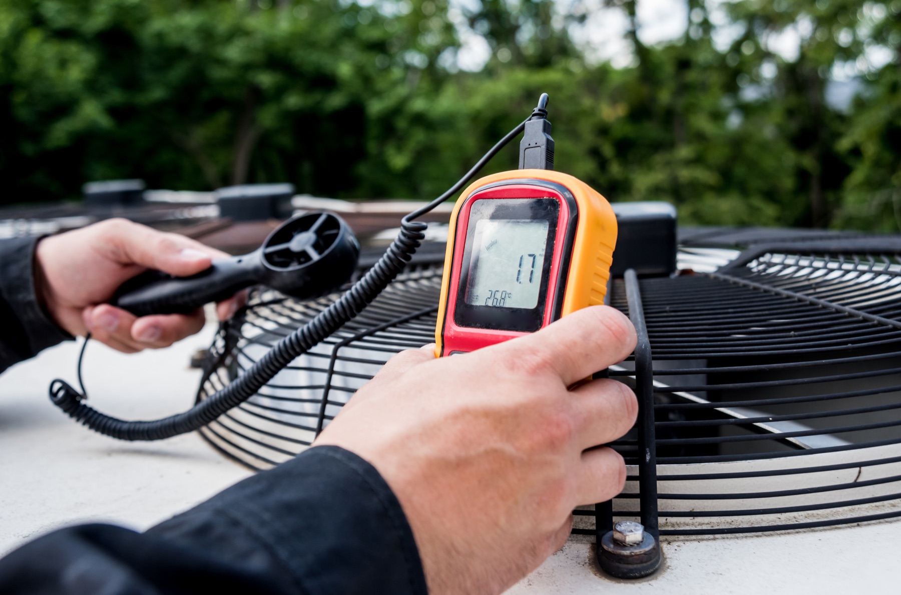 Hands checking airflow with a measuring tool