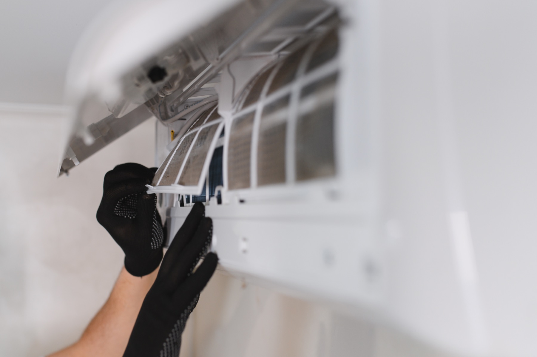 Gloved hands replacing an indoor air filter
