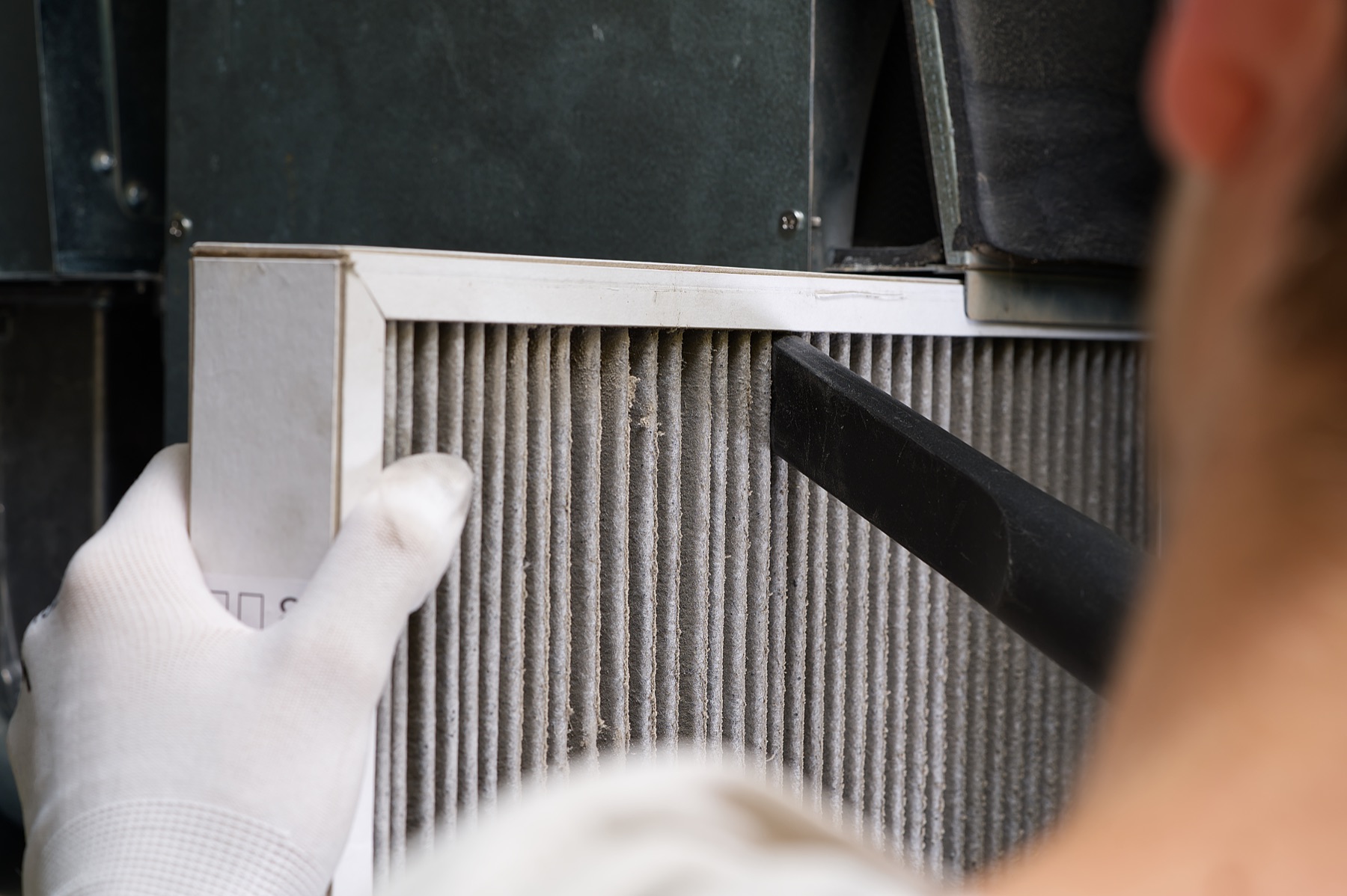 Gloved hands cleaning an HVAC air filter