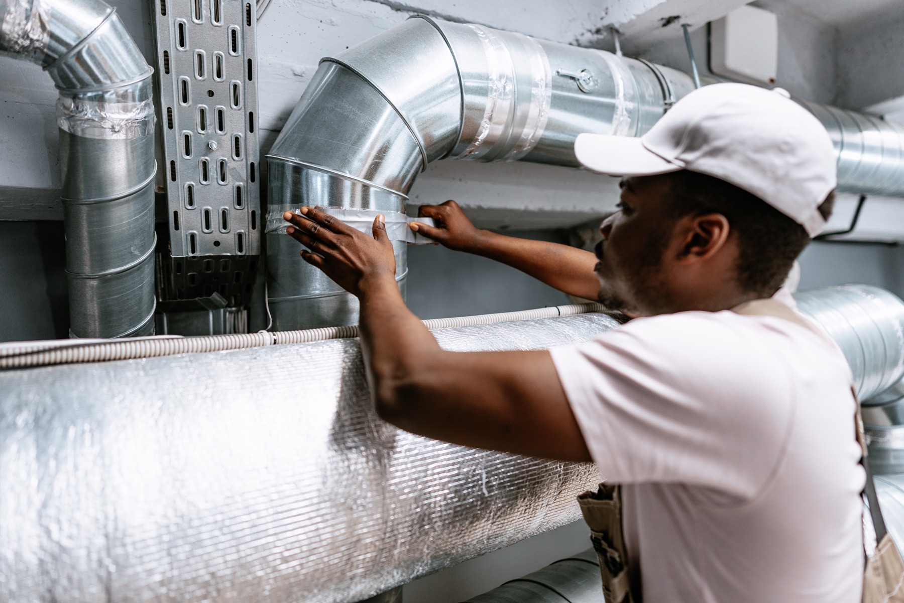 Technician sealing ductwork with foil tape
