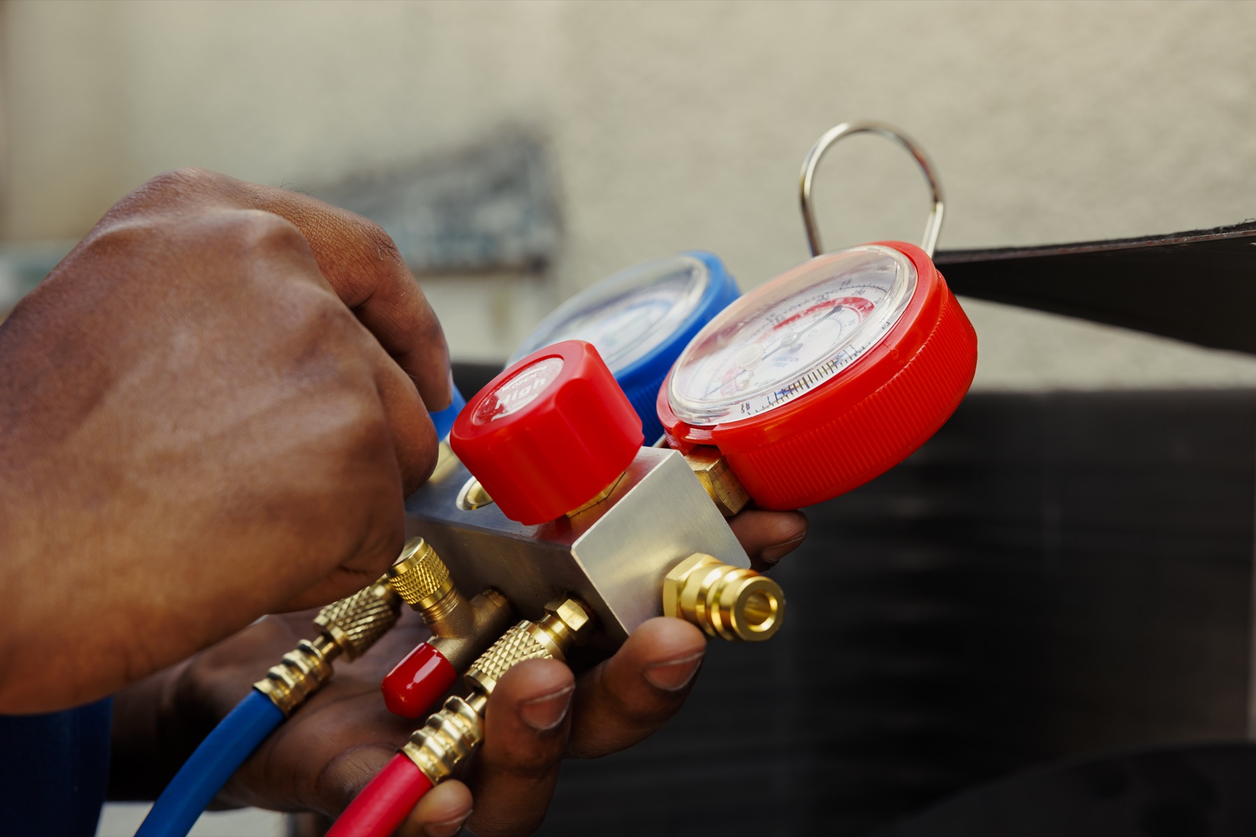 Hands checking HVAC pressure with a manifold gauge