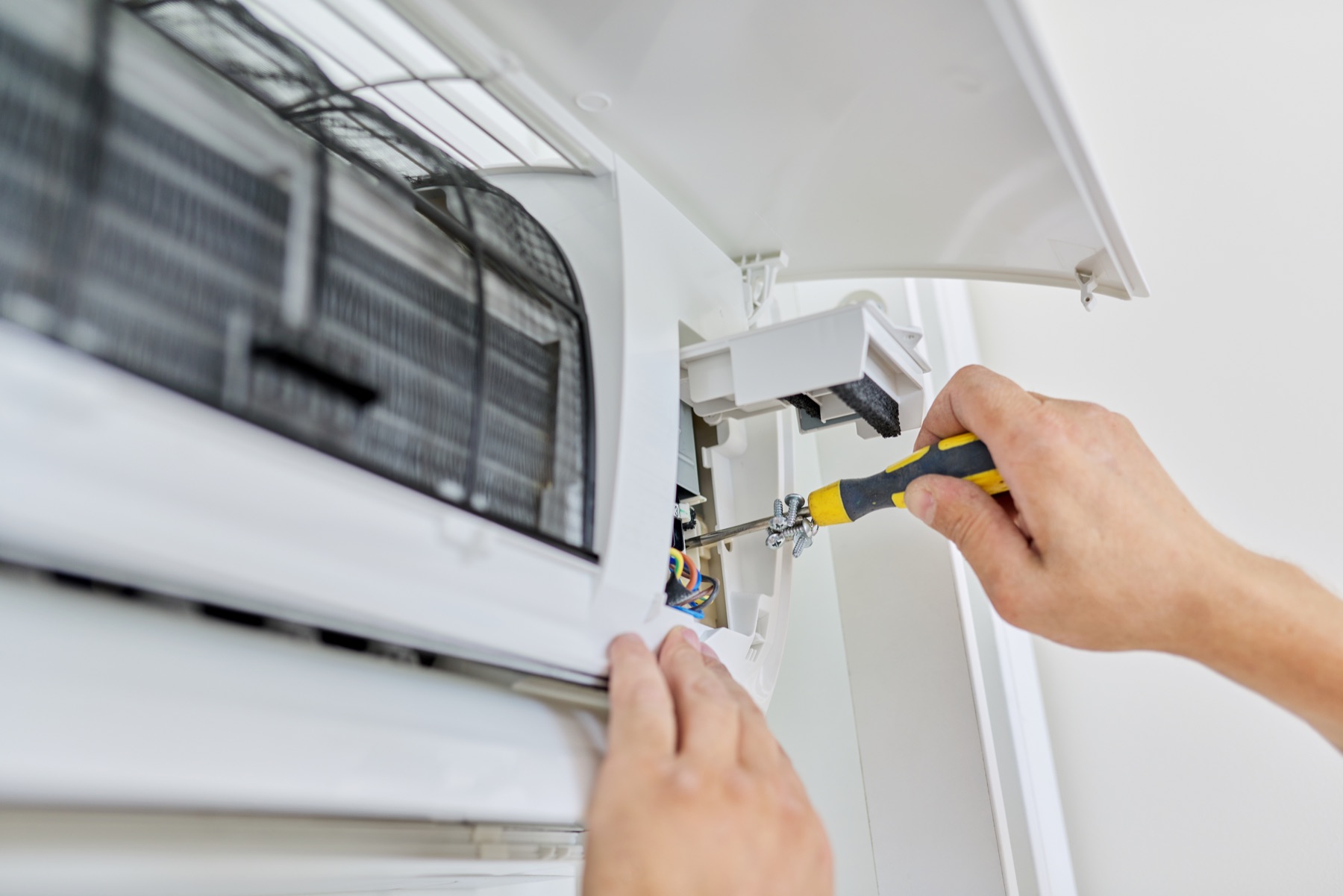 Technician using a screwdriver on an indoor cooling unit