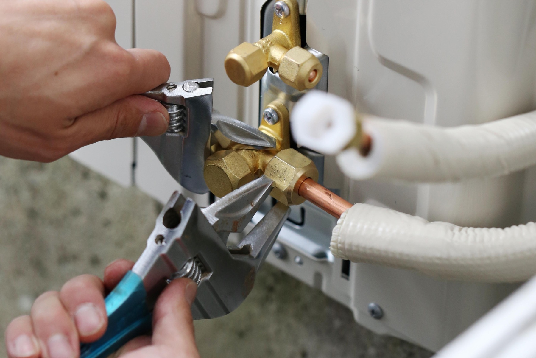 Hands tightening air-conditioning line connections