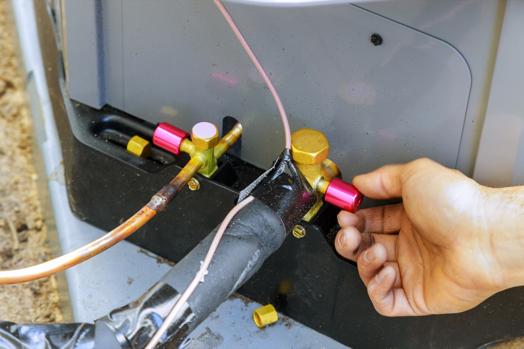 Hands servicing air-conditioning refrigerant connections